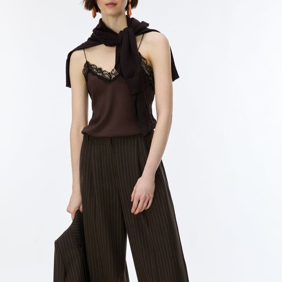 A model wearing a dark brown sleeveless top with lace trim and a matching draped scarf, paired with dark brown pleated wide-leg trousers, against a plain white studio background.