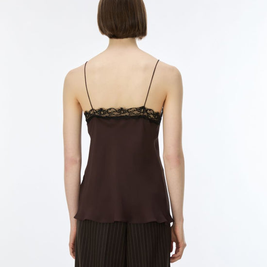A model shown from the back wearing a dark brown camisole top with black lace trim at the neckline and matching dark pleated trousers, against a plain white studio background.