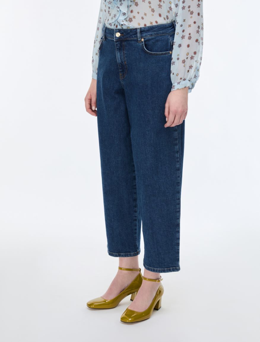 Person wearing blue jeans and a patterned top on a white background