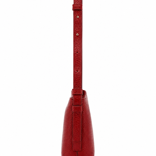 A red textured leather shoulder bag shown from the back, featuring a long matching strap and a vertical strap detail on the back panel, set against a plain white background.