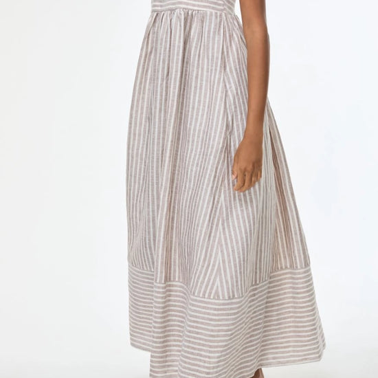 Woman wearing a long striped dress on a white background