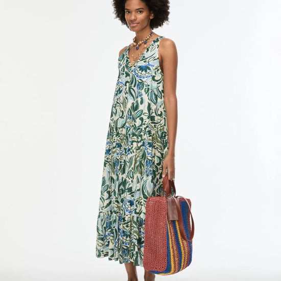 model wearing green floral print dress carrying bag on white background