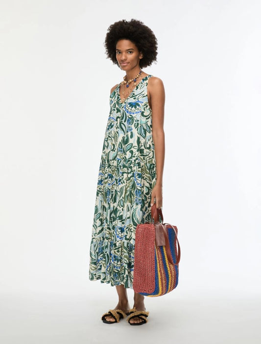 model wearing green floral print dress carrying bag on white background