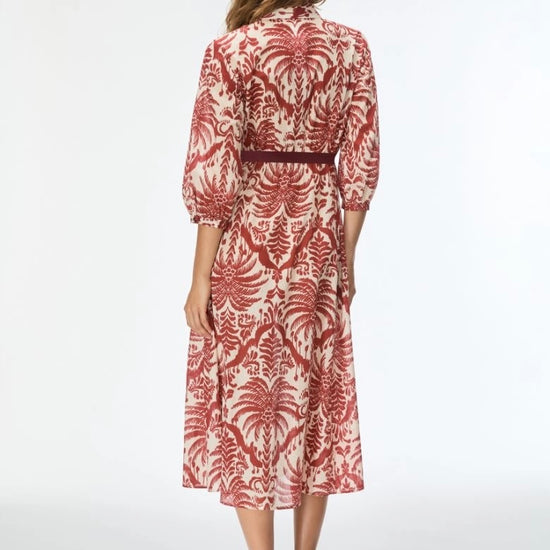 Woman wearing a red and white patterned dress on a white background