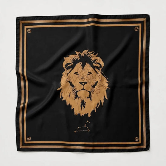 A square black scarf featuring a large gold lion head illustration in the center, bordered by double gold stripes and small gold decorative motifs in the corners, laid flat against a light gray background.