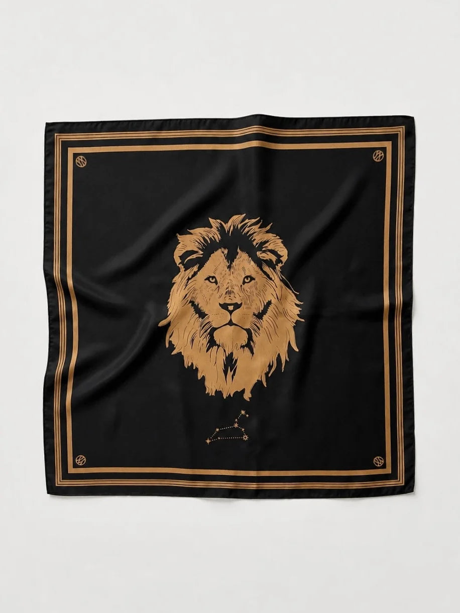 A square black scarf featuring a large gold lion head illustration in the center, bordered by double gold stripes and small gold decorative motifs in the corners, laid flat against a light gray background.