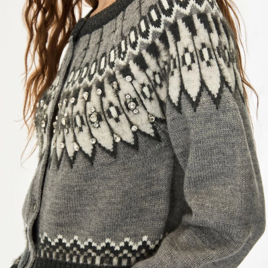 A close-up of a gray knit cardigan sweater with a black and off-white Fair Isle pattern across the yoke and cuffs, worn by a model.