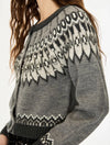 A close-up of a gray knit cardigan sweater with a black and off-white Fair Isle pattern across the yoke and cuffs, worn by a model.
