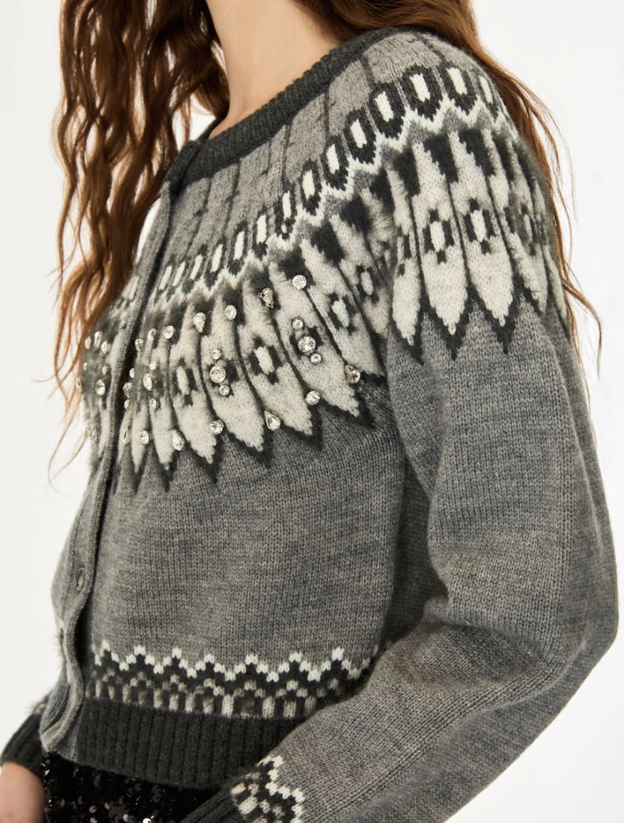 A close-up of a gray knit cardigan sweater with a black and off-white Fair Isle pattern across the yoke and cuffs, worn by a model.
