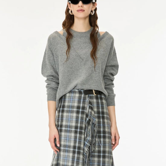 A model wearing a gray knit sweater with shoulder cutouts and a blue-gray plaid skirt, styled with black sunglasses and a headband against a plain white background.