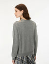A woman shown from the back wearing a heather gray knit sweater with a wide collar and a plaid skirt, photographed against a plain light gray studio background.