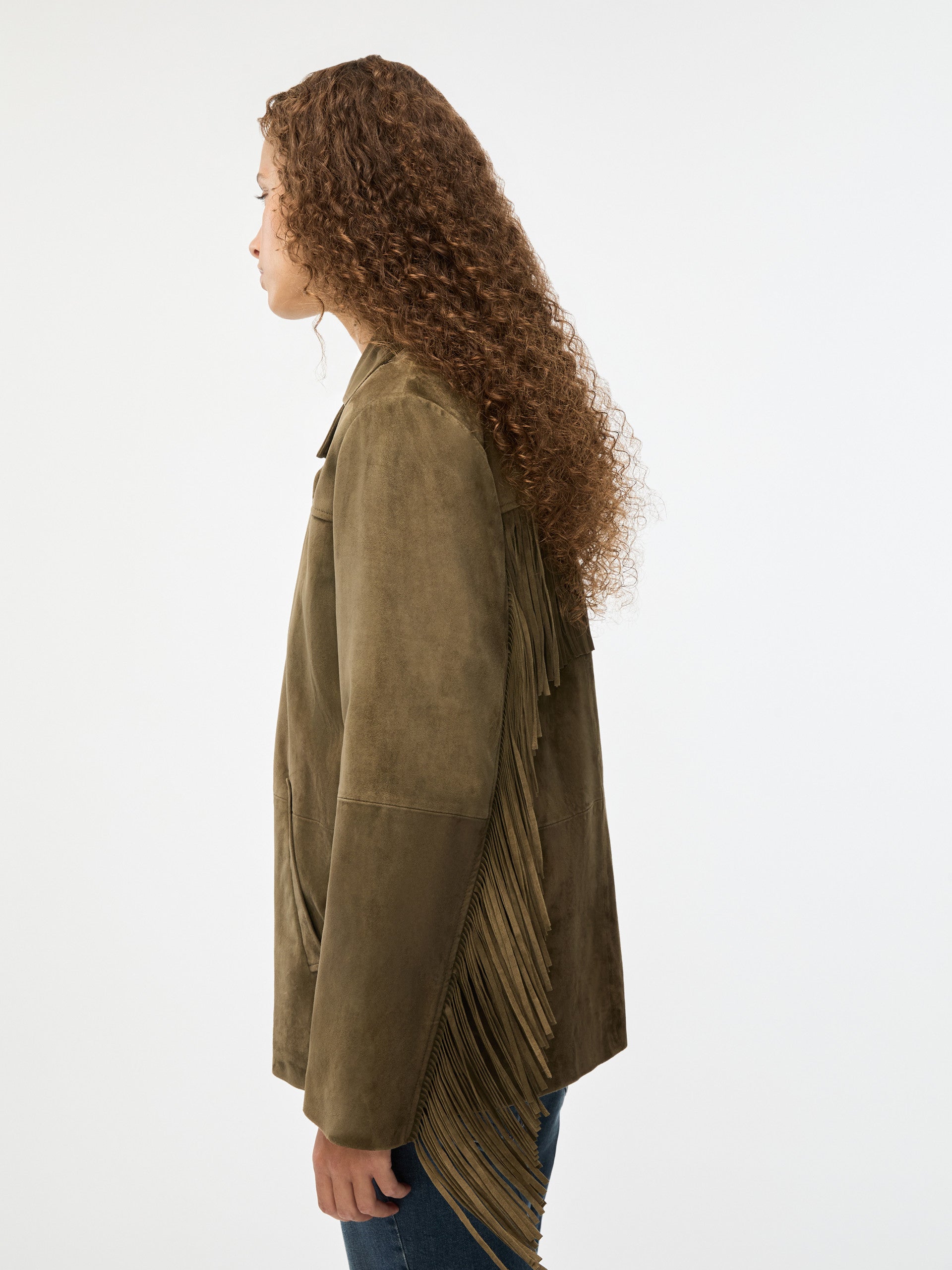 Woman wearing a green jacket with pleated details on a white background