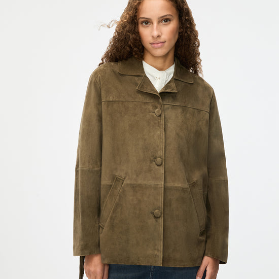 Woman wearing a green suede jacket on a white background