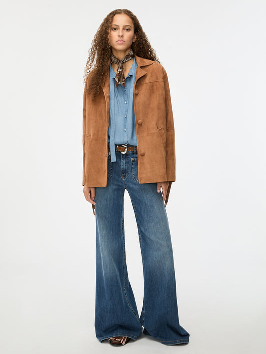 Woman wearing a brown coat, blue shirt, and jeans on a white background