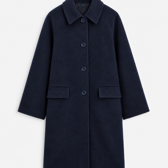 A woman modeling a dark navy blue wool-blend coat with front buttons, paired with light blue jeans and brown shoes, standing against a plain white studio background.