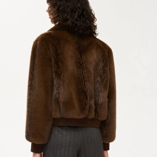 Person wearing a brown fur jacket on a white background rear view