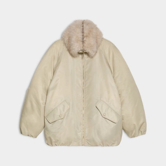 A light beige puffer jacket with a fluffy faux-fur trimmed hood, displayed flat against a light gray background.