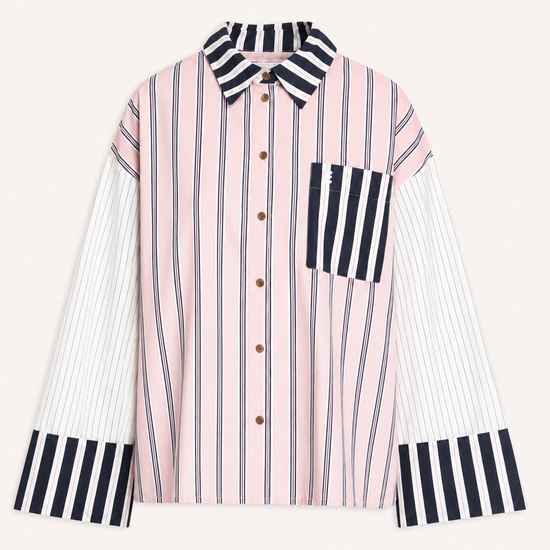 A long-sleeve button-up shirt with a pink and white vertical stripe body, contrasting black and white striped collar, chest pocket, and cuffs, displayed on a light cream background.