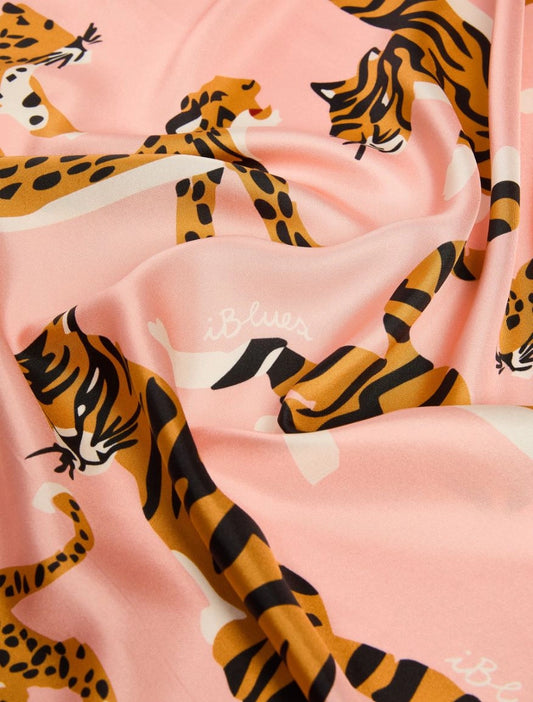 A close-up of a pink fabric with a repeating print of orange and black tiger and leopard animals, plus small white script logos.