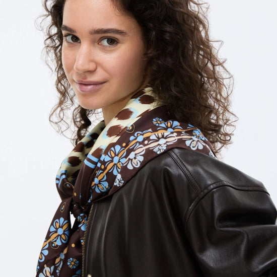 Woman wearing a black leather jacket with a patterned scarf on a white background