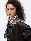 Woman wearing a black leather jacket with a patterned scarf on a white background