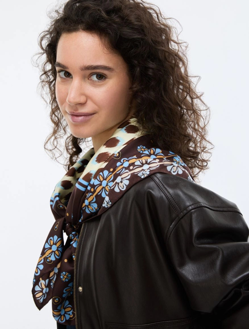 Woman wearing a black leather jacket with a patterned scarf on a white background
