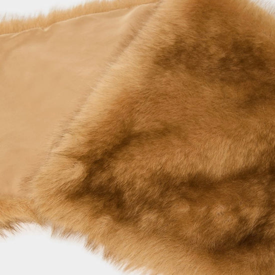 A close-up of a tan faux fur trim or collar with a smooth beige lining, shown against a plain white background.