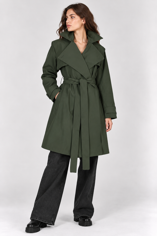 model wearing a short green trench coat with black jeans on a plain white  background 