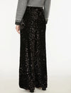 A person wearing a long black sequined maxi skirt with a gray long-sleeve top featuring a black and white patterned knit cuff, shown from the back against a plain white studio background.