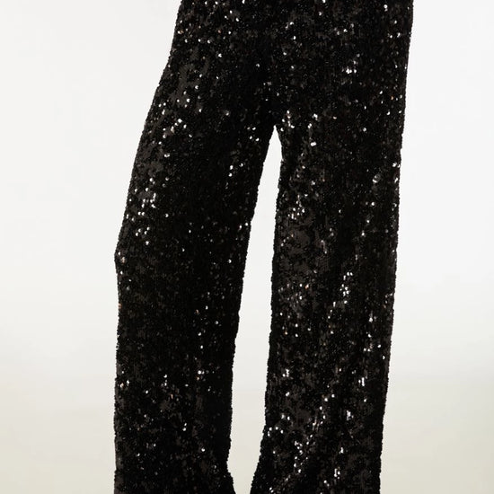 Black sequined wide-leg pants with a glittering silver sparkle effect, shown on a model from the waist down against a plain white background.
