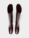 A pair of glossy, knee-high boots in a deep burgundy color, shown from a top-down view against a plain light gray background.