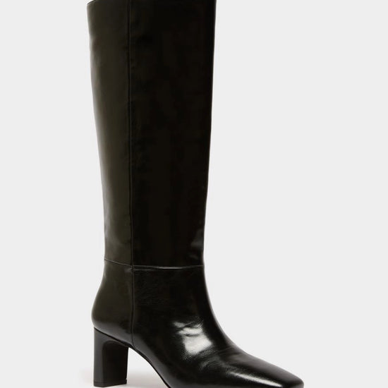 A single black knee-high boot with a glossy patent leather finish, a pointed toe, and a chunky block heel, shown against a plain light gray background.