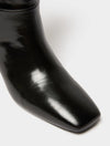 Close-up of a glossy black leather ankle boot with a square toe on a clean white background.