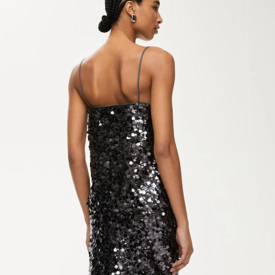 Rear view of woman wearing charcoal sequin top with matching skirt