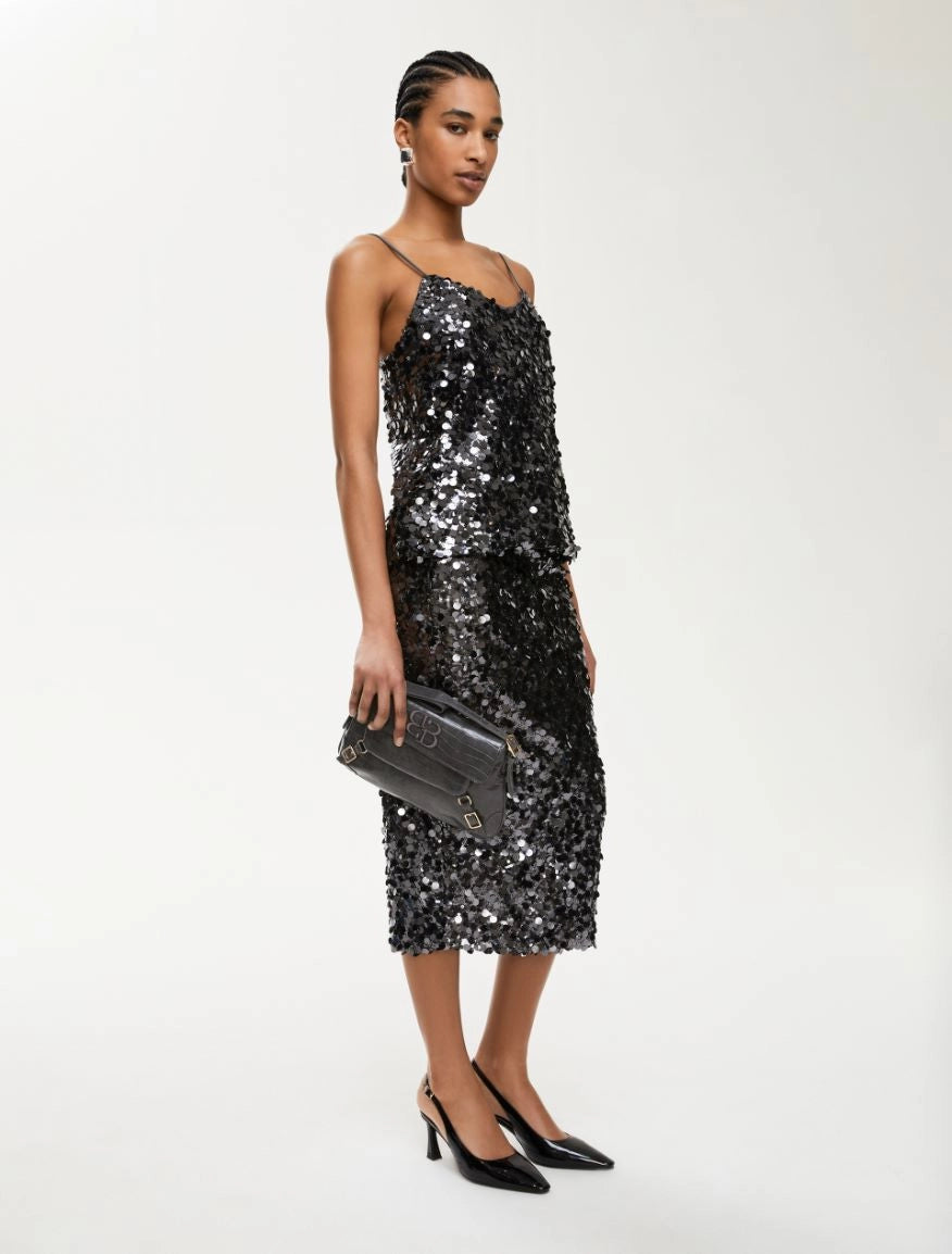 Full length image of woman wearing charcoal sequin top and matching skirt with black heels and black handbag