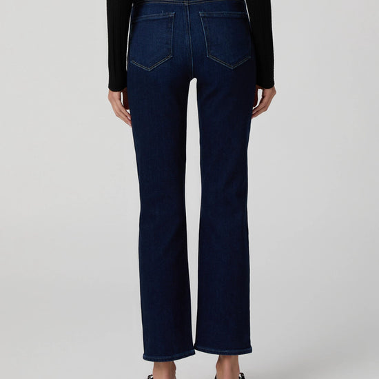 Person wearing dark blue jeans on a white background rear view