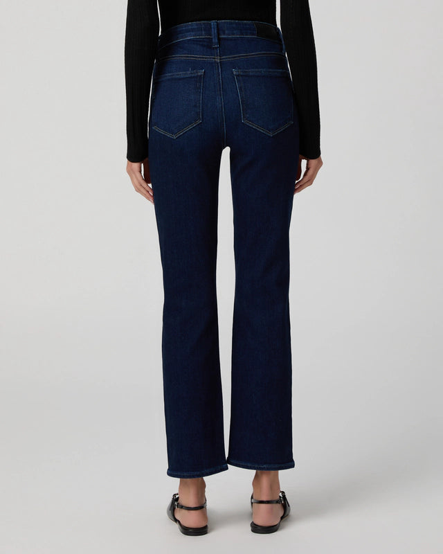 Person wearing dark blue jeans on a white background rear view