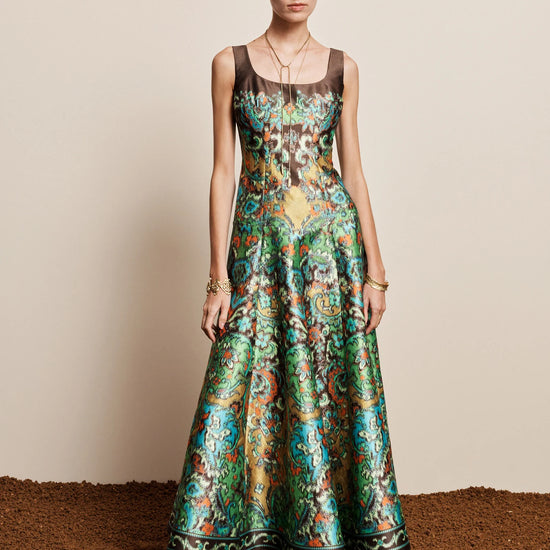 Woman wearing a patterned dress standing on a textured surface with a neutral background