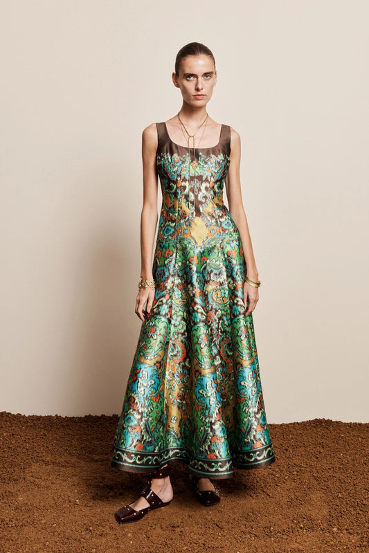 Woman wearing a patterned dress standing on a textured surface with a neutral background