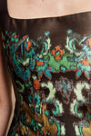 Close-up of a strapless top or dress featuring a dark brown base with a vibrant, multicolored abstract ikat pattern in teal, green, orange, and light blue.