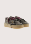 A low-top platform sneaker in dark gray suede and leather, featuring a thick beige gum sole, gray laces, and burgundy ribbon laces tied in a bow.