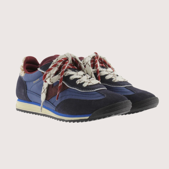 A low-top fashion sneaker, featuring navy blue suede and mesh panels, burgundy accents, patterned white and burgundy laces, and a cream midsole, shown against a plain light gray background.