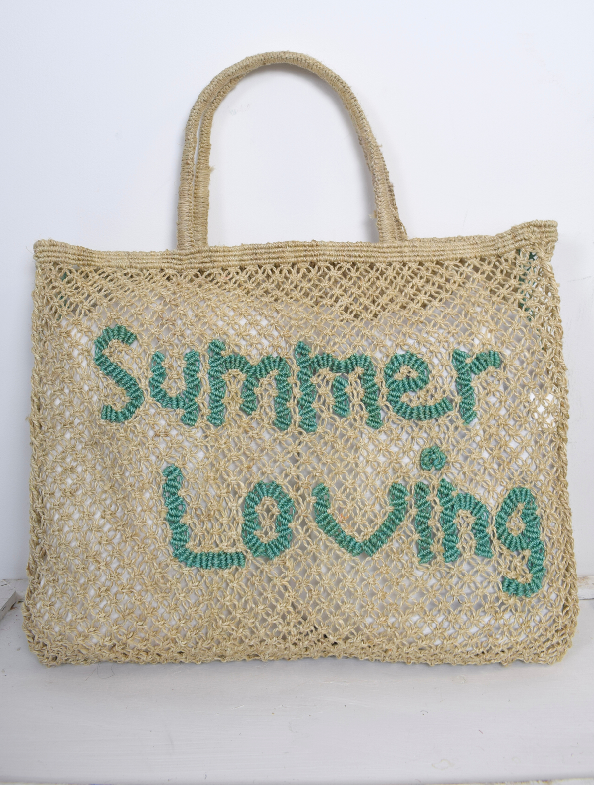 Neautral woven bag with blue writing saying 'summer loving' on 