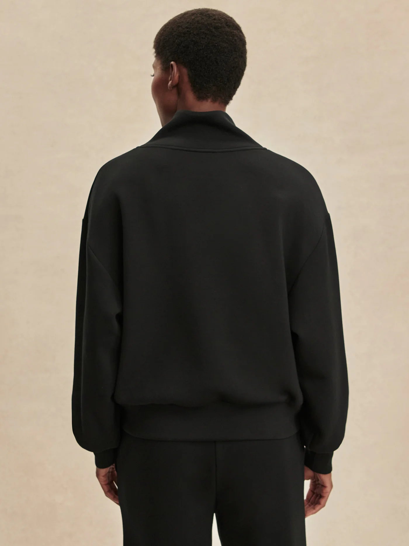 Quarter zip and slightly cropped black sweat top with shawl collar and V neckline from varley rear view