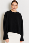 model wearing a black crew neck sweater and a white skirt on a plane background 