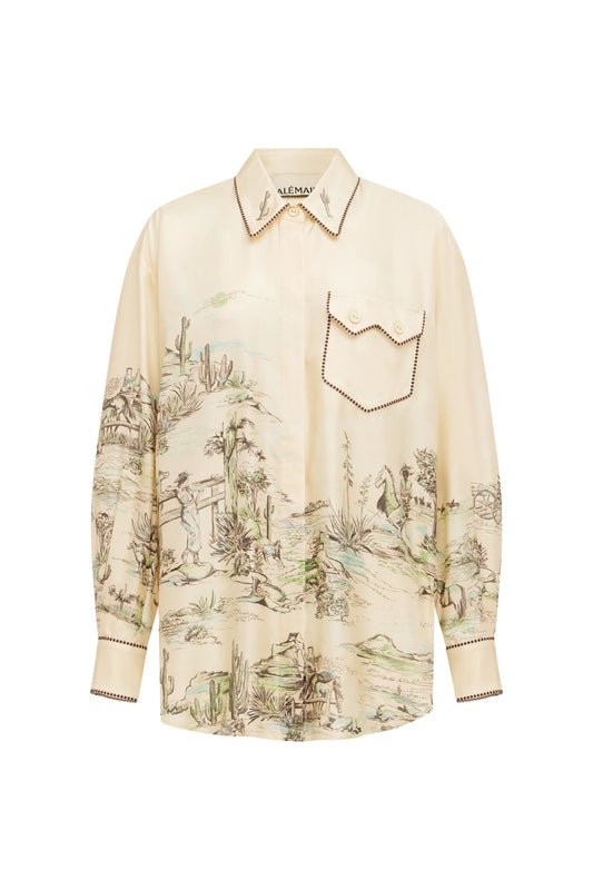 A cream-colored long-sleeve button-up shirt with a detailed scenic landscape print in muted green and brown tones, featuring a chest pocket with decorative stitching.