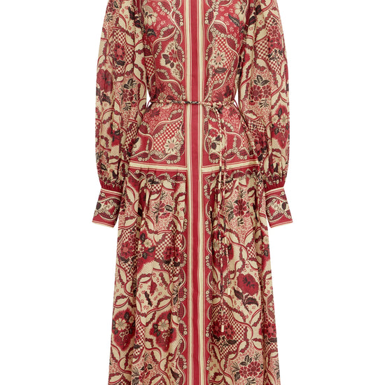 A long-sleeve collared maxi shirt dress with a red, beige, and black botanical pattern, featuring a self-tie waist belt, shown against a plain white background.