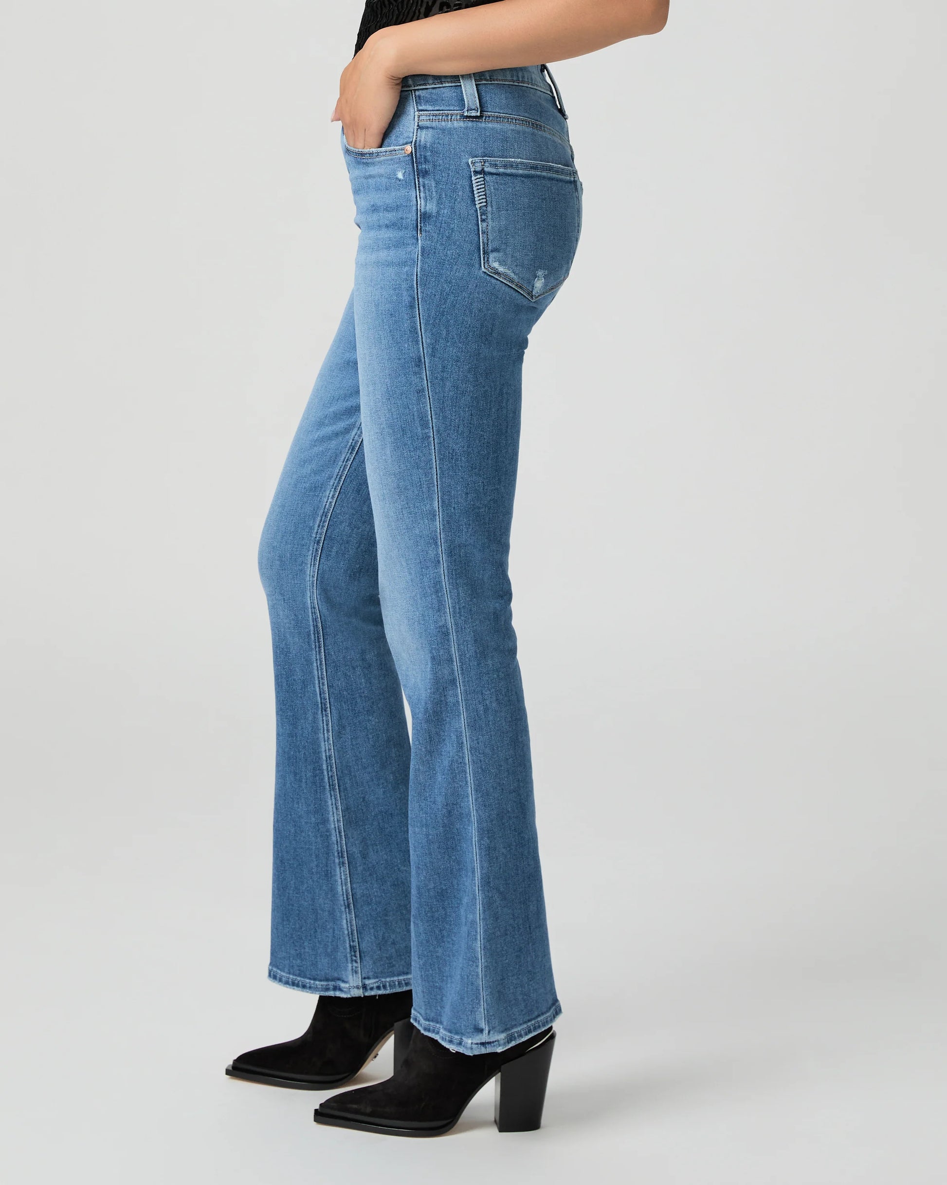 Blue jeans by Paige worn by a person on a white background side view