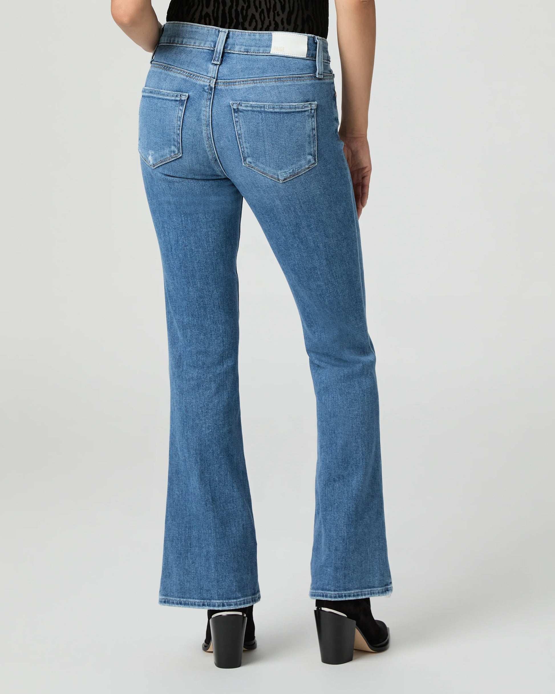 Blue jeans by Paige worn by a person on a white background rear view