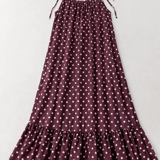 Plum coloured polka dot dress with thin straps on a light gray background